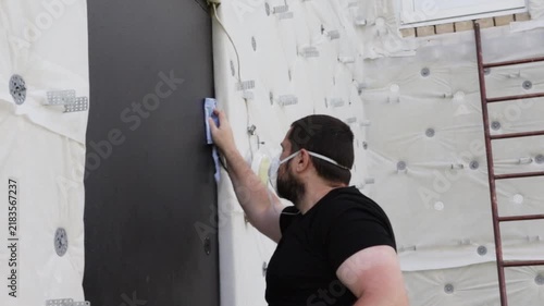 homeowner wearing a respirator cleaning an old steel entrance door with cloth and solvent before painting, showing surface degreasing and safe renovation preparation