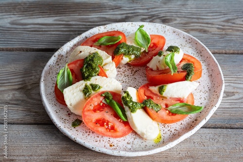 Caprese salad with juicy tomatoes, fresh mozzarella and pesto. Concept for a tasty and healthy appetizer, flat lay. Italian food, cuisine.
