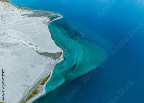 Aerial view of the turquoise waters of a high altitude lake meeting the white sandy shores in Ladakh Division, Ladakh, India.