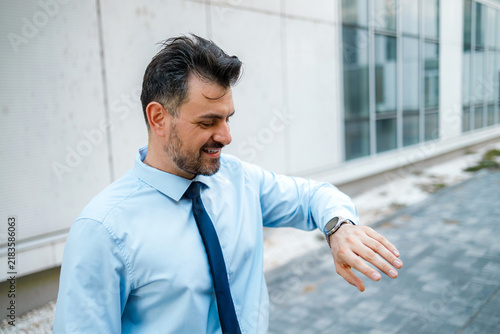 Фотография Man checking watch while standing outside a modern building