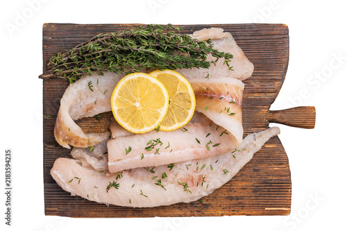 Fotografie Haddock sea fish fillets, raw whitefish on a wooden board ready for cooking isolated on white background