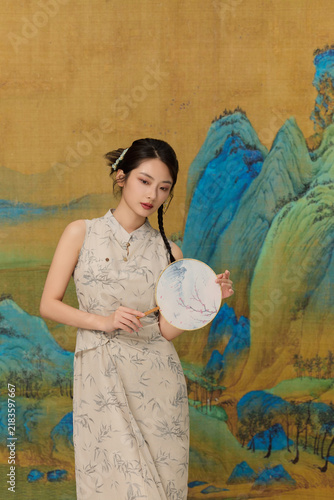 Quadro su tela Young woman in traditional Chinese style dress holding round fan against painted