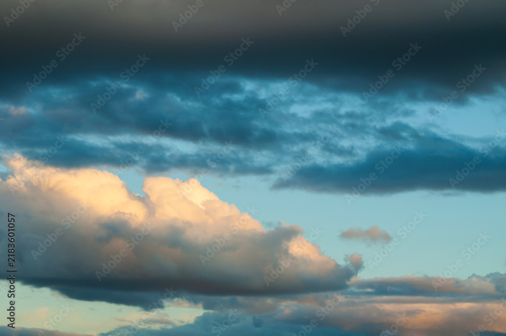 Obraz premium Dramatic sky background. Layers of dark blue clouds at the top and sides. A bright golden cloud formation glowing with sunlight