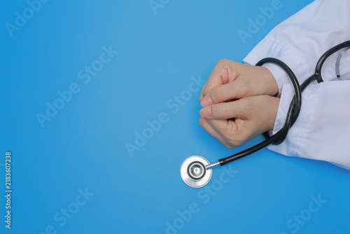 Doctor displays deep integrity with bound hand by black stethoscope against blue background facing heavy medical stress with anxious mood