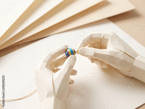 Artistic Hands Holding Colorful Bead for Crafting on Neutral Background with Paper Layers