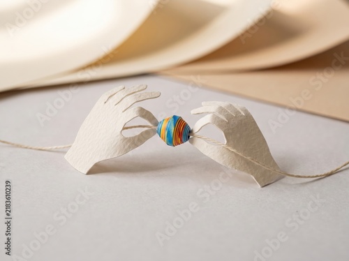 Hands Holding Colorful Paper Bead in Creative Paper Craft Artwork Displaying Intricate Design