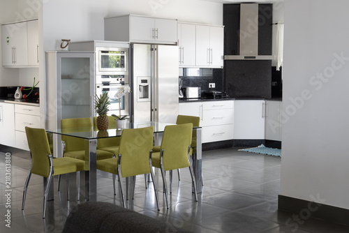 Modern rental apartment with equipped kitchen, glass dining table and stylish upholstered chairs indoors