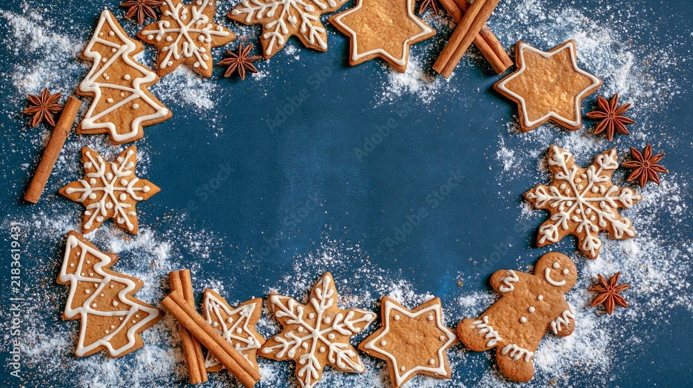 Obraz premium Merry Christmas advent xmas celebration holiday concept - Frame made of gingerbread men, star anise and cinnamon sticks, isolated on blue table background, top view