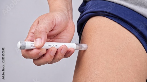 Man Holding Insulin Pen And Injecting Medication Into His Thigh At Home, For Diabetes Treatment And Glucose Management