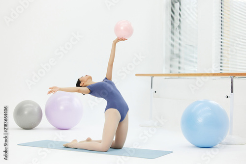 Obraz na płótnie Young female gymnast stretching with pink ball in bright studio