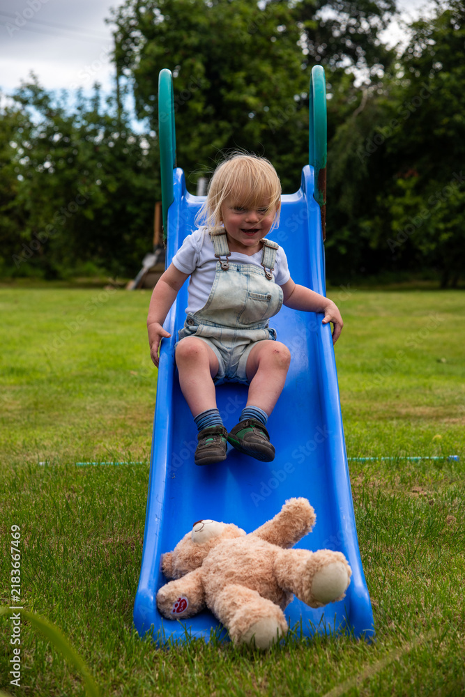 Obraz premium Child slides with teddy outdoors.