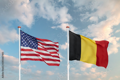 Waving American and German flag in front of a blue sky