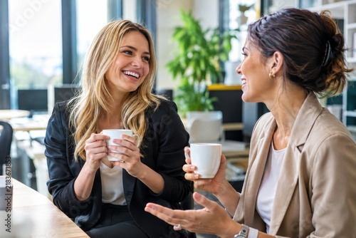 Zwei junge Frauen im Büro reden gut gelaunt miteinander