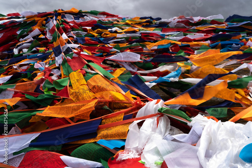 Фотография Dense pile of colorful Tibetan prayer flags fluttering under overcast sky in Tib