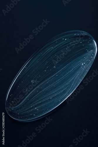 Close-up macro shot of translucent jellyfish-like organism suspended in water droplets, ethereal blue bioluminescent glow, scientific underwater photography, microscopic life form, dark background