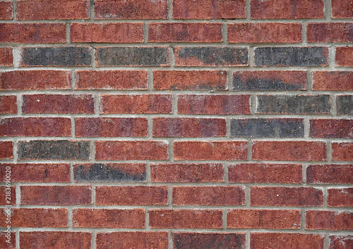 Fotografie Horizontal view of red and black textured brick and mortar wall surface with por