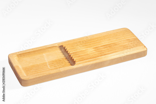 Obraz na płótnie Light wood cheese slicer with grooved surface and angled cutting slot on white b