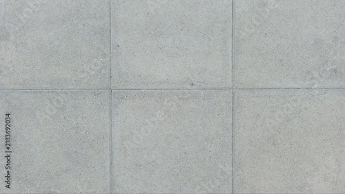 Grey square concrete paving blocks texture. Minimal grey stone paver wall and floor background. Top view grid pattern of outdoor concrete pavers on sidewalk floor.