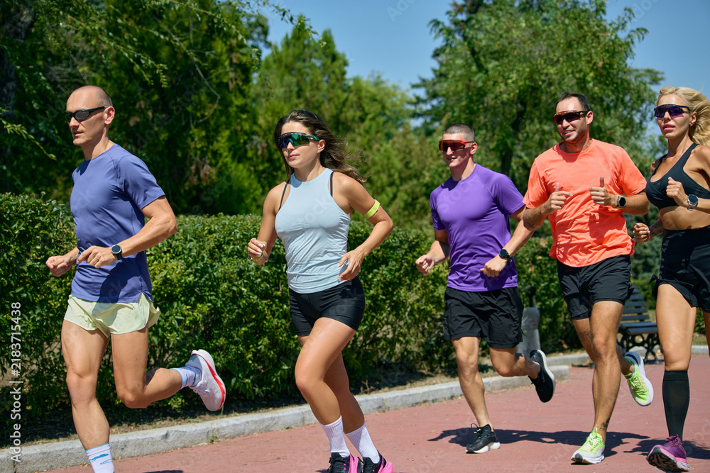 Obraz premium Close side view of diverse runners training together in bright summer sunlight. Concept of performance training, athletic lifestyle and shared progress.