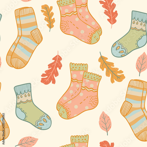 Cartoon autumn seamless pattern with cozy socks and fallen leaves. Vector illustration on off white background.