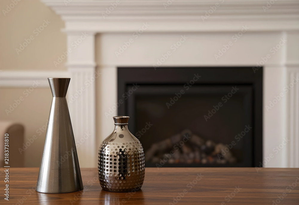 Obraz premium Interior design and home decor, modern metal vases on a wooden table in a cozy living room with a fireplace background for lifestyle and real estate