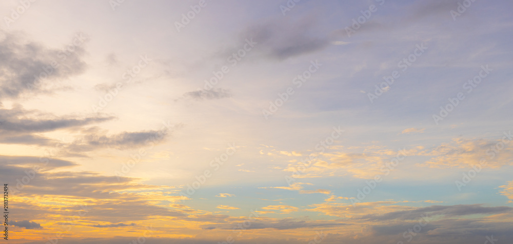 Obraz premium Soft sunset sky with golden glow and pastel purple clouds,A beautiful panoramic view of a soft sunset sky featuring a warm golden glow near the horizon blending into gentle pastel purple and light.