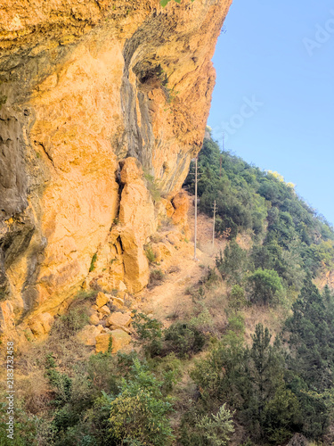 Konstfotografi Golden sunlit limestone overhang and wooden utility poles on a wooded canyon slo
