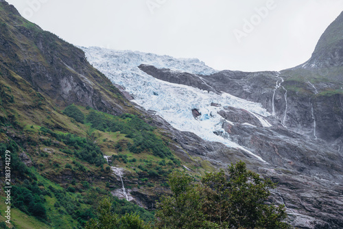 Obraz na płótnie Glacier flowing down rocky mountains with waterfalls