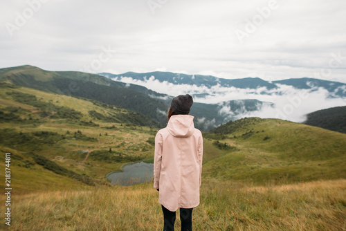 young woman in a raincoat hiking in the mountains