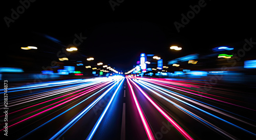 A long tunnel stretches into the distance, illuminated by streaks of vibrant light from passing vehicles. The road is a blur of motion, creating a dynamic and energetic scene.
