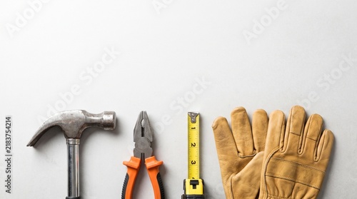 Assorted construction tools and leather gloves arranged neatly on a clean white surface background.