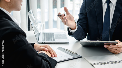 Man employer holding resume of applicant to reading her profile during asking candidate question and explaining