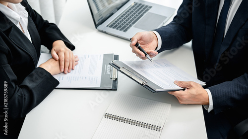 Man employer holding pen to pointing on resume and asking candid