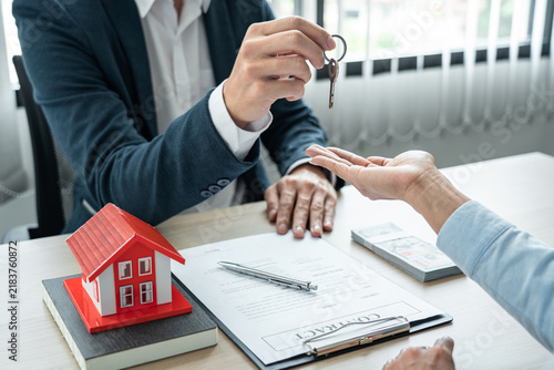 Foto Real estate broker agent holding filing keys to the customer after signing renta