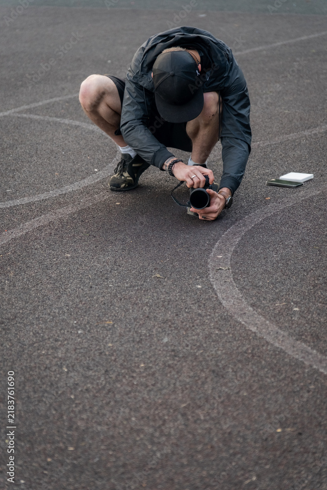 Fototapeta premium Photographer crouches on a basketball court to capture close-up shots of the surface
