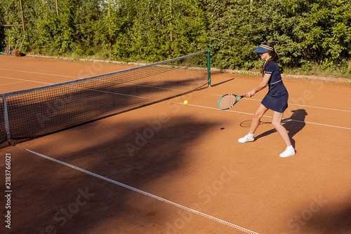 фотографія Woman playing a low forehand near the net, tennis technique on a sunny clay cour