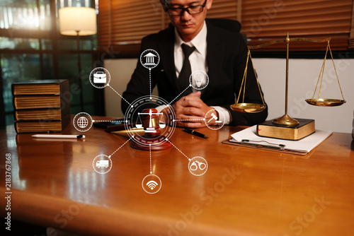 Asian Lawyer Sitting at Desk with Scales of Justice and Connected Digital Icons