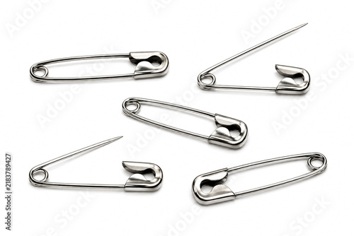 Silver metal safety pins scattered isolated on white background.
