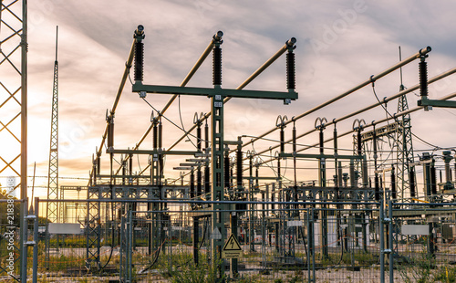 Electrical substation equipment with high voltage disconnectors and insulators at sunset, power grid infrastructure and energy distribution concept