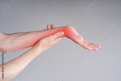 Close up of man massaging painful left arm with red highlighted spot, inflammation of wrist joint, carpal tunnel syndrome medical concept