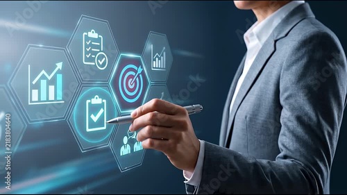 Businessman hand pointing pen at target goal hexagon icon with growth chart and checklist hologram, representing business strategy planning, performance tracking and management technology concept