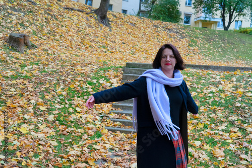 Woman holding bouquet of yellow autumn leaves in park with blanket of fallen leaves, with woman, smile, autumn, leave detail, showing yellow, maple, bouquet, park context