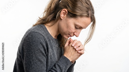 Side view of a thoughtful woman with hands clasped in prayer or meditation, expressing deep gratitude and spiritual devotion against a clean white background