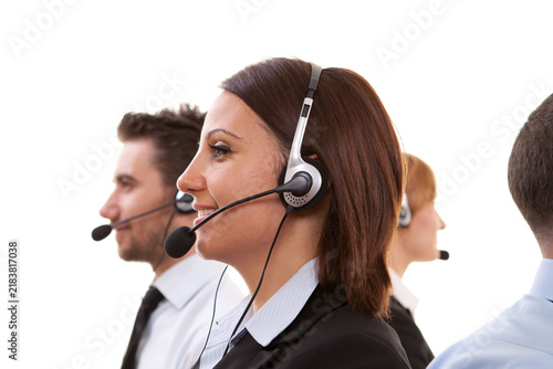 Side view profile of smiling brunette female call center agent with headset working with team isolated on white background.