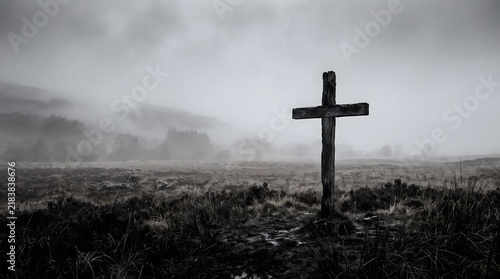 A solitary wooden cross standing in a dark and moody field under a heavy overcast stormy sky