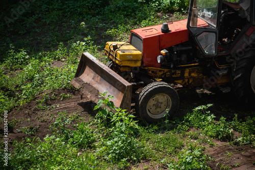 Rusty Tractor With Front Blade Clearing Soil In Green Field Agricultural Earthmoving Equipment