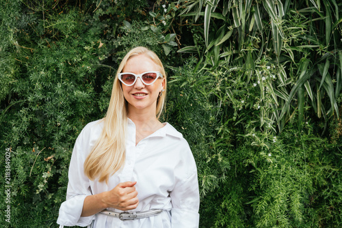 Blonde woman wearing sunglasses in green foliage