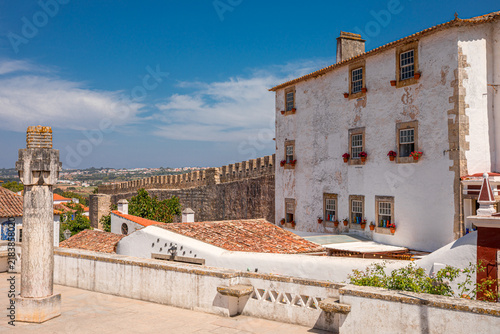 Historic Pelourinho column and traditional white building in Obidos, Portugal