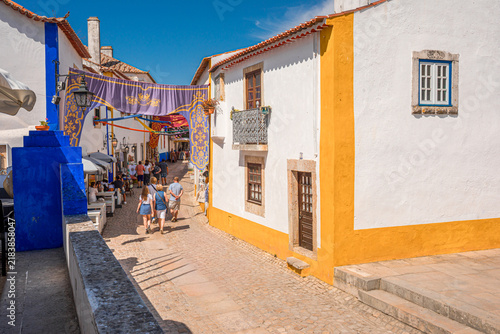 Traditional cobblestone street decorated with banners in historic Obidos, Portugal.