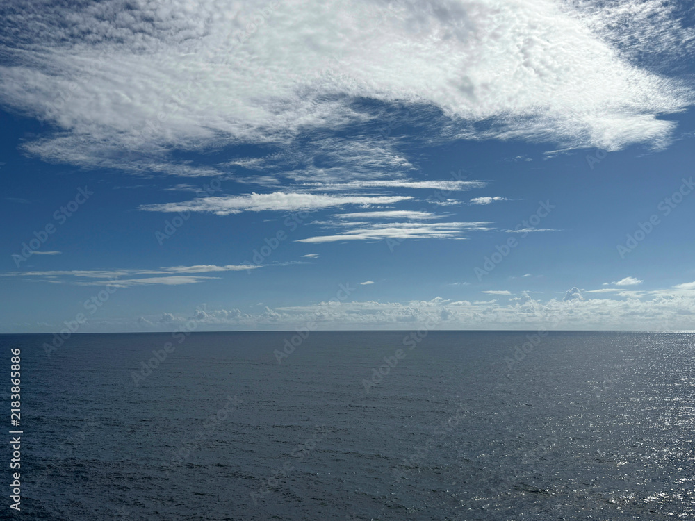 Obraz premium Ocean blue glittering waters and blue sky with beautiful white clouds 